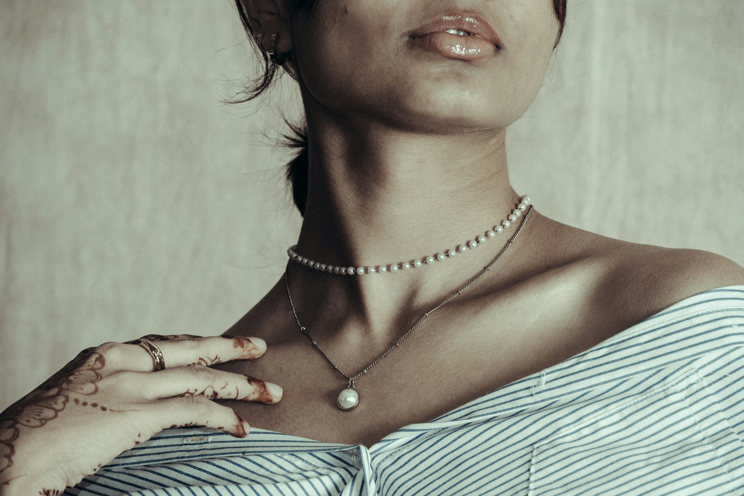 Mulher de camisa listrada usando colares de pérola