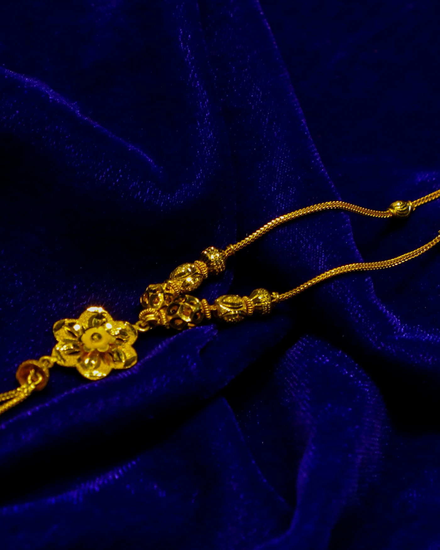 Colar dourado com pingente de flor sobre tecido azul