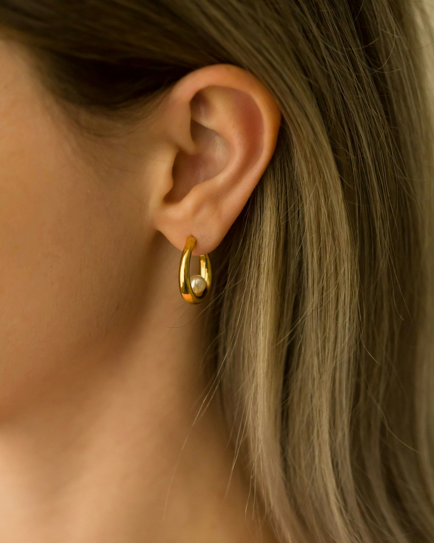 Close de orelha com brinco dourado
